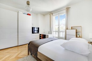 Ein Hotelzimmer mit Bett, Fernseher, Schreibtisch, Kleiderschrank und einem Fenster mit Blick.