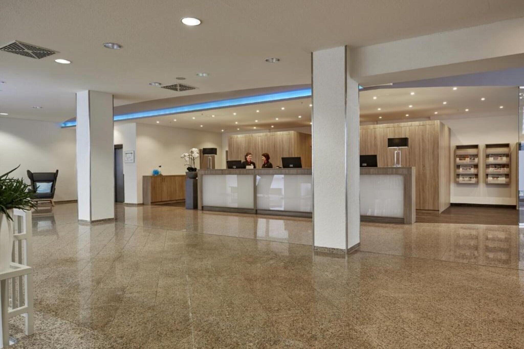 Eine moderne Hotelhalle mit einer Rezeption, einer Lounge und einer Pflanze.