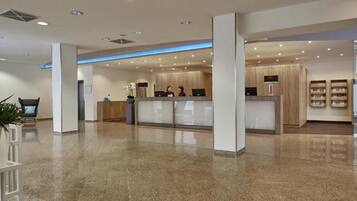 Eine moderne Hotelhalle mit einer Rezeption, einer Lounge und einer Pflanze.