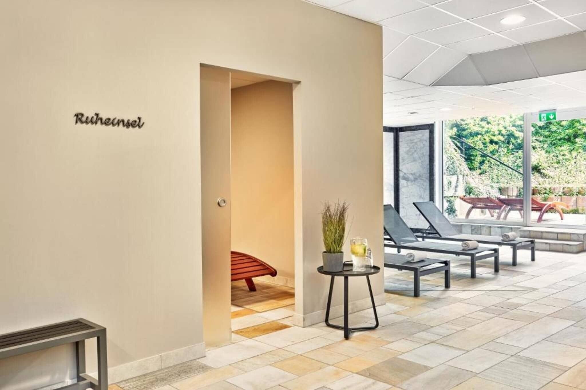 Un hall de hotel con una recepción, una zona de estar con sillones y vistas al exterior.