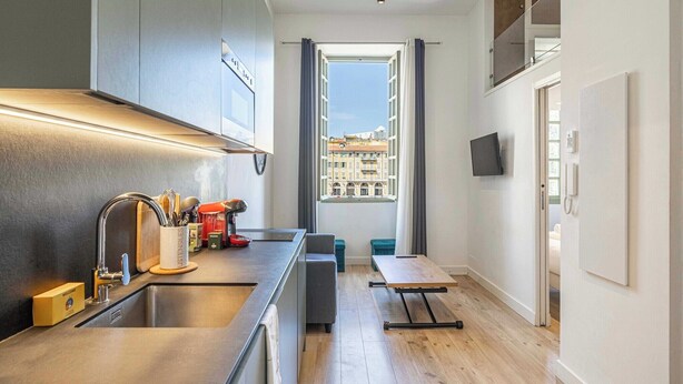 Ett modernt kök med en inbyggd ugn, en diskho och ett fönster med gardiner.