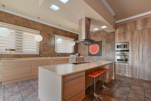 Eine moderne Küche mit Kochinsel, Barhocker, eingebauten Geräten und einer Musterküchenrückwand.
