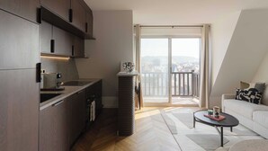 Een moderne keuken met donkerhouten kastjes, een inbouwoven en een groot raam met uitzicht op een balkon.