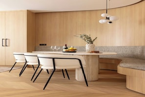 A modern kitchen with a curved island, white chairs, and a hanging light fixture. - Apt Exceptionnel - AC - 3BR-8P- Gare de l'Est (Paris)