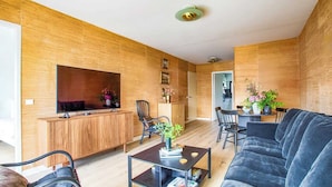 Ein modernes Wohnzimmer mit einer Couch, einem Couchtisch und einem an der Wand montierten Fernseher.