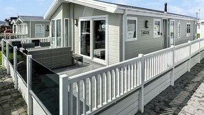 A row of mobile homes with a covered deck and a white railing. - Willerby Portland - UKC9613 (Towyn)
