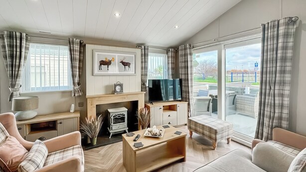 A modern living room with a fireplace, sofa, coffee table, and a TV. - Willerby Portland - UKC9613 (Towyn)