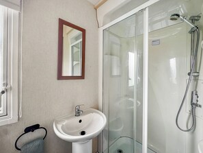 A bathroom with a sink, mirror, and glass shower enclosure. - ABI St David - UKC9615 (Towyn)