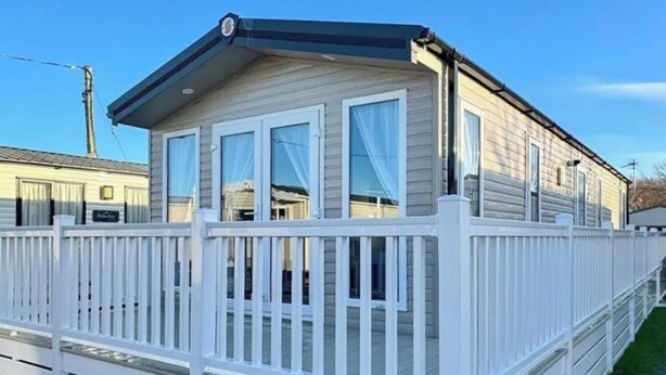 A mobile home with a white exterior, a porch with white railings, and a clear sky. - Sunseeker Y Wyddfa - UKC9637 (Towyn)