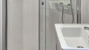 A bathroom with a glass-enclosed shower, a white sink, and a mirror. - Sunseeker Y Wyddfa - UKC9637 (Towyn)