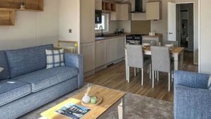 A modern living room with a sofa, a dining table, and a kitchen area with cabinets and appliances. - Sunseeker Y Wyddfa - UKC9637 (Towyn)