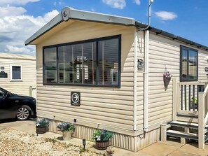 Una casa móvil con un ventanal grande, un porche pequeño y un buzón.