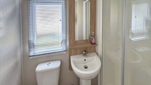 Un bagno con il water, un lavandino e una finestra dotata di persiane.
