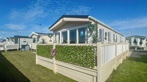 Una hilera de casas móviles con techo plano, ventanas grandes y fachada blanca.