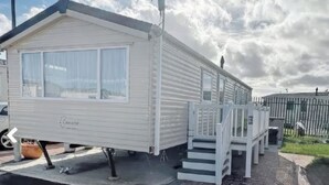 Une maison mobile blanche, dotée d’un porche abrité et d’un petit escalier.