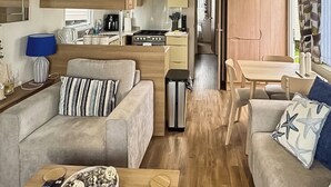 A modern living room with two sofas, a coffee table, and a dining area. - Swift Escape - UKC9641 (Towyn)