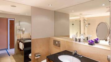 A modern bathroom with a large mirror, a sink, a toilet, and a shower area.