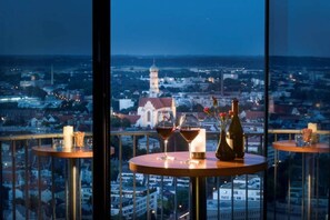 A balcony with a city view, a table with candles, and two glasses of red wine. - Sunday an der Kongresshalle Augsburg Standard Single Room (Augsburg)