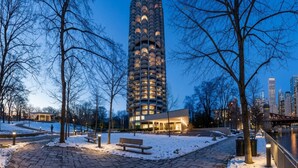 Korkea rakennus, jossa on ainutlaatuinen arkkitehtoninen ilme, ja sen ympärillä on puisto, jossa on kävelyreittejä ja penkkejä.