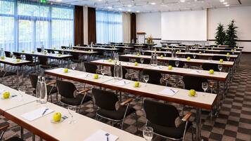 A conference room with multiple tables, chairs, and a projector screen.