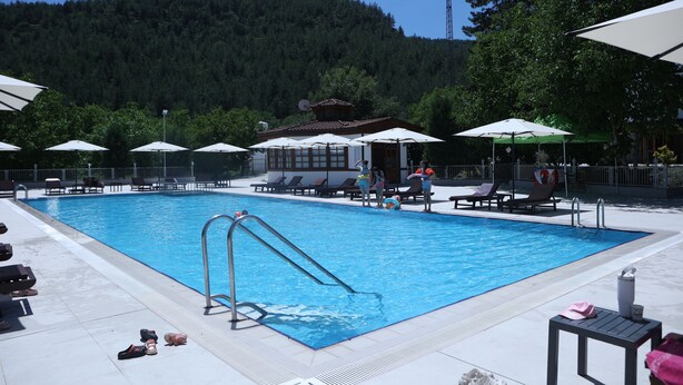 A swimming pool with a diving board, lounge chairs, and umbrellas.