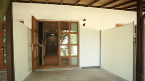 A hallway leading to a room with a sliding glass door, a light fixture, and a concrete floor.