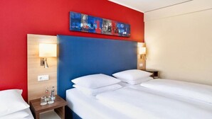 A hotel room with a bed, bedside tables, a nightstand, and a painting on the wall.