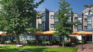 A hotel courtyard with outdoor seating, a small water feature, and a building with multiple floors and balconies.