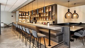 Eine moderne Bar mit einer langen Theke, Barhocker und Pendelleuchten.