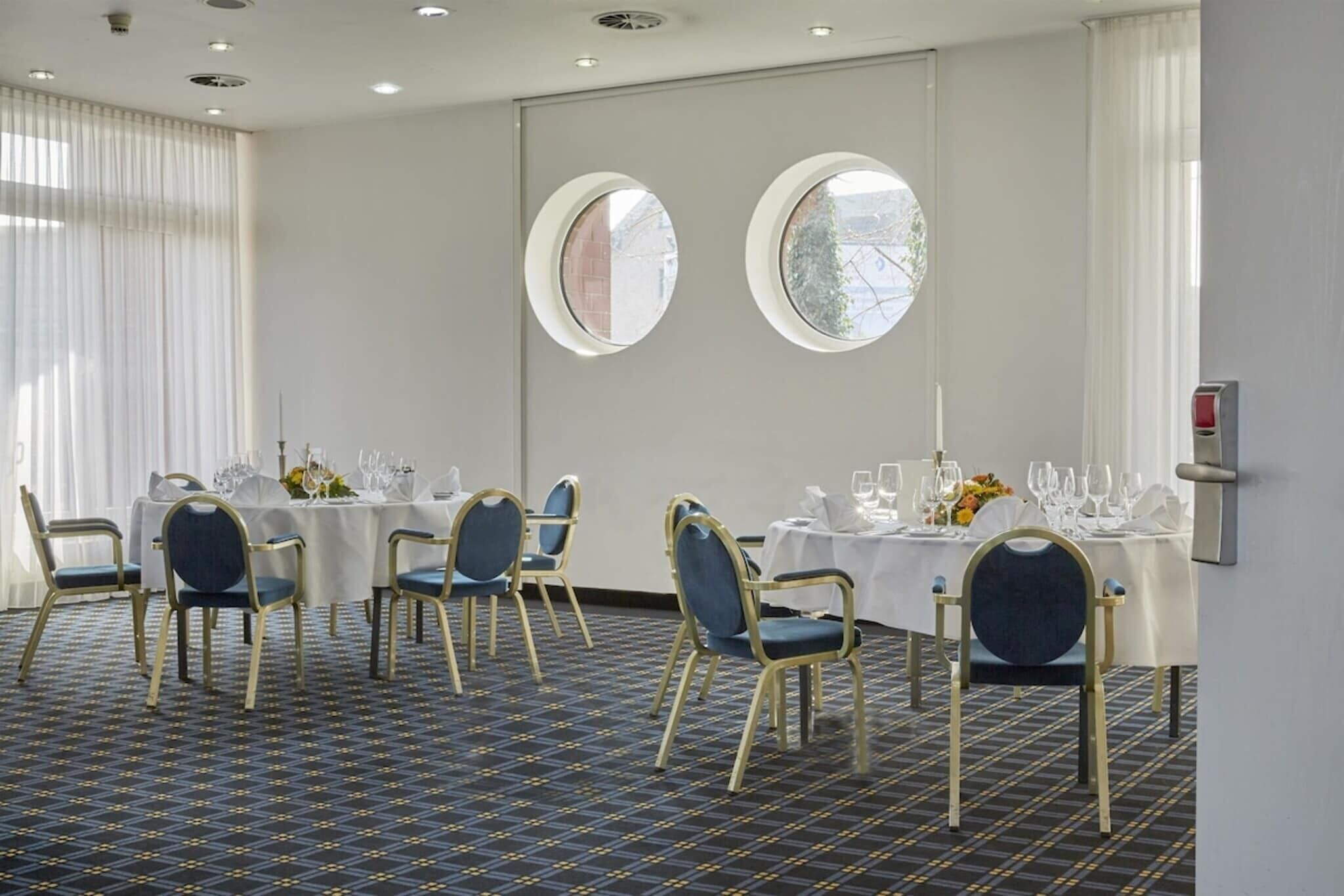 A conference room with round tables, chairs, and a patterned floor.