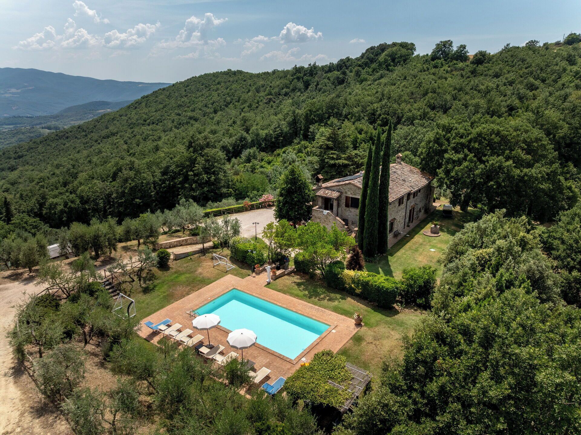 Una villa con piscina, rodeada de exuberante vegetación y colinas.
