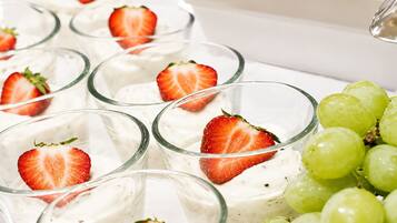 A dessert tray with individual servings of a white creamy dessert topped with strawberries and garnished with grapes.