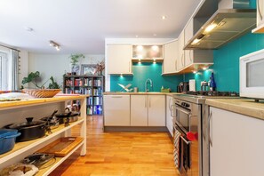 A modern kitchen with white cabinets, a teal backsplash, and wooden flooring. - Leafy Leith 2BDR Retreat with a Private Balcony (Edinburgh)