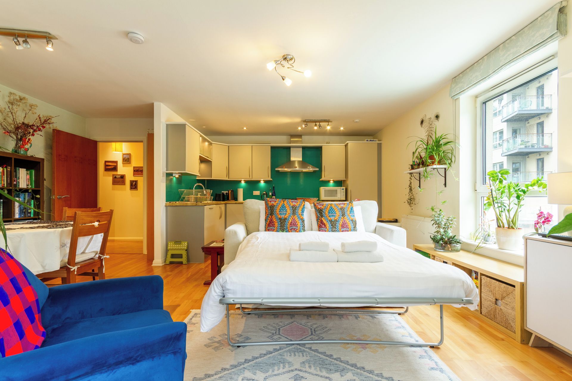 Une chambre d’hôtel compacte comprenant un lit, une petite kitchenette, un coin repas et une vue sur la ville.