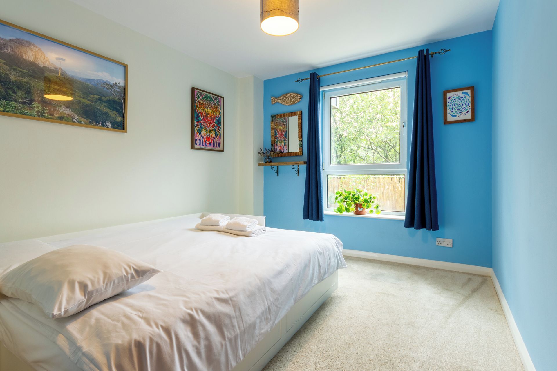 Un dormitorio con cama, ventana con cortinas y decoración en la pared.