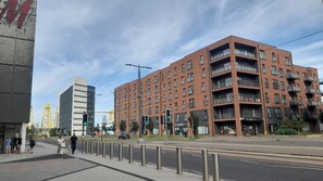 A multi-story building with a brick facade, balconies, and a visible storefront with signage. - Leafy Leith 2BDR Retreat with a Private Balcony (Edinburgh)