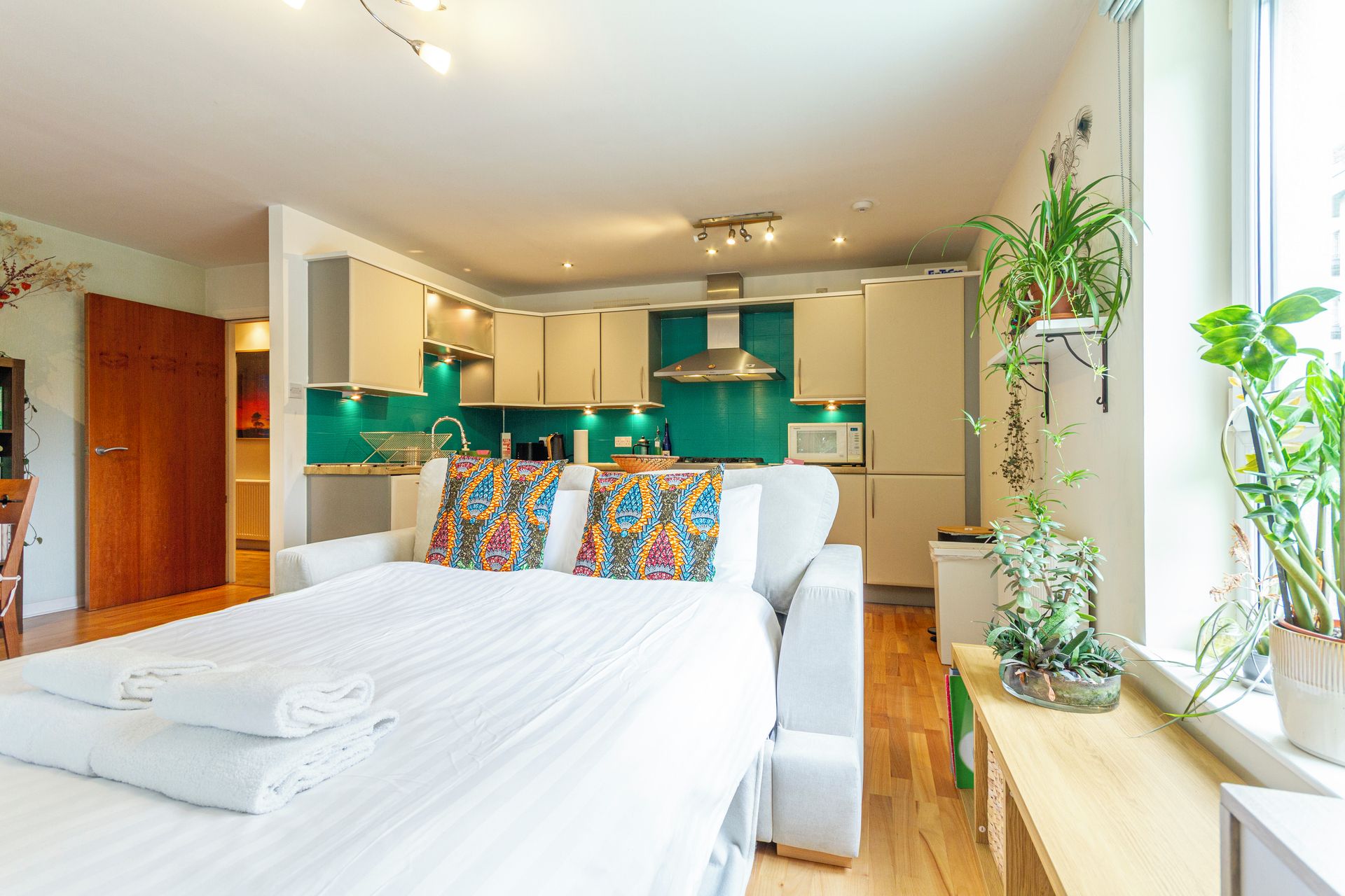Une chambre moderne avec un grand lit, une table de chevet et une fenêtre ornée de plantes.