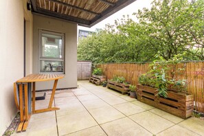 A patio with a wooden table and benches, surrounded by a bamboo fence and potted plants. - Leafy Leith 2BDR Retreat with a Private Balcony (Edinburgh)