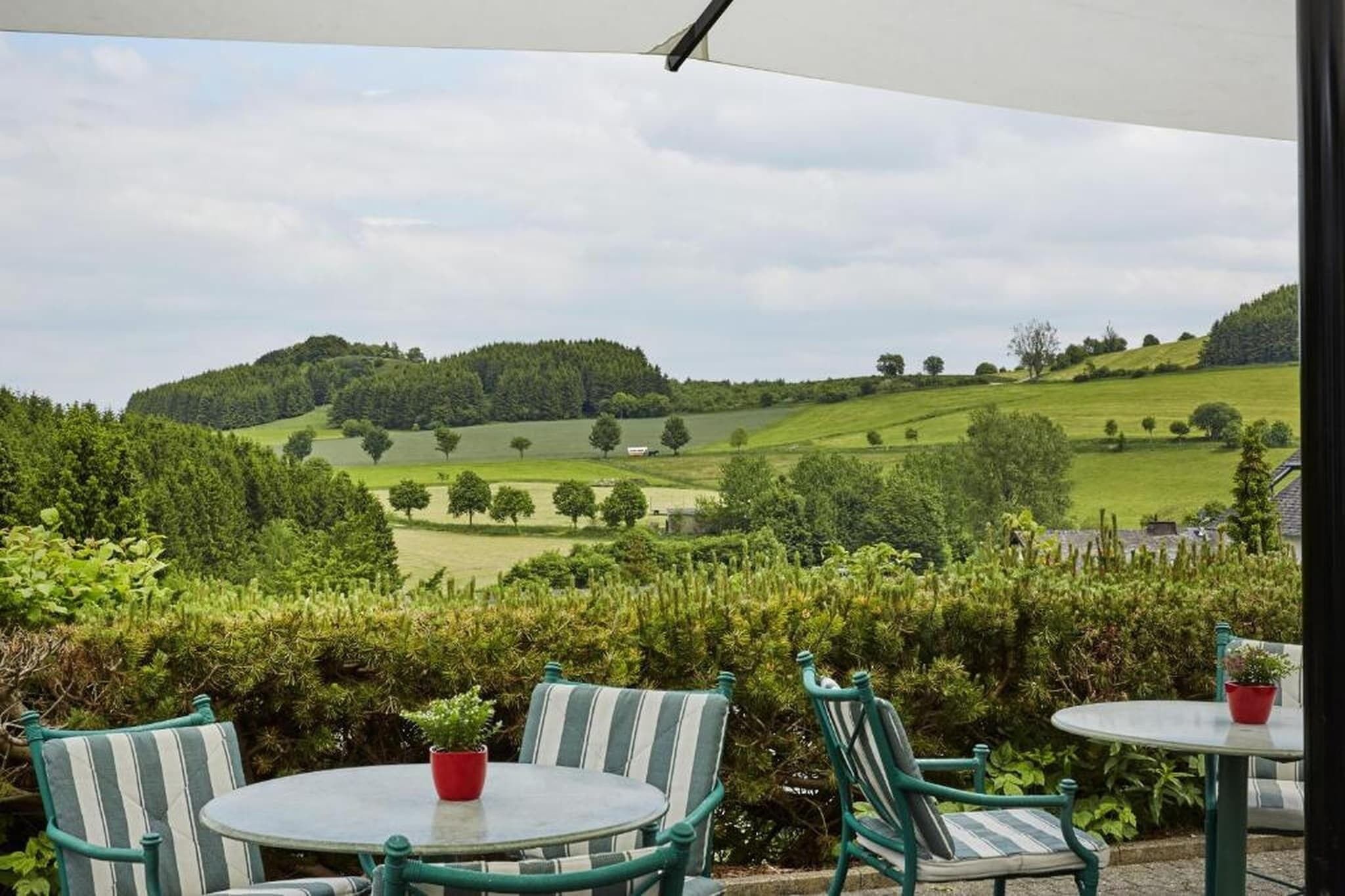 Un patio con sillas y una mesa, con vistas a un paisaje verde y colinas.