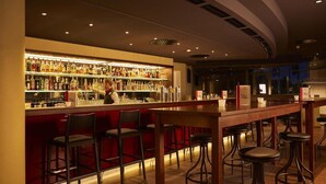 Zona de bar con un cantinero, una amplia variedad de licores y varios taburetes.