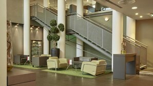 Un vestíbulo con una escalera, zona de estar y mostrador de recepción.