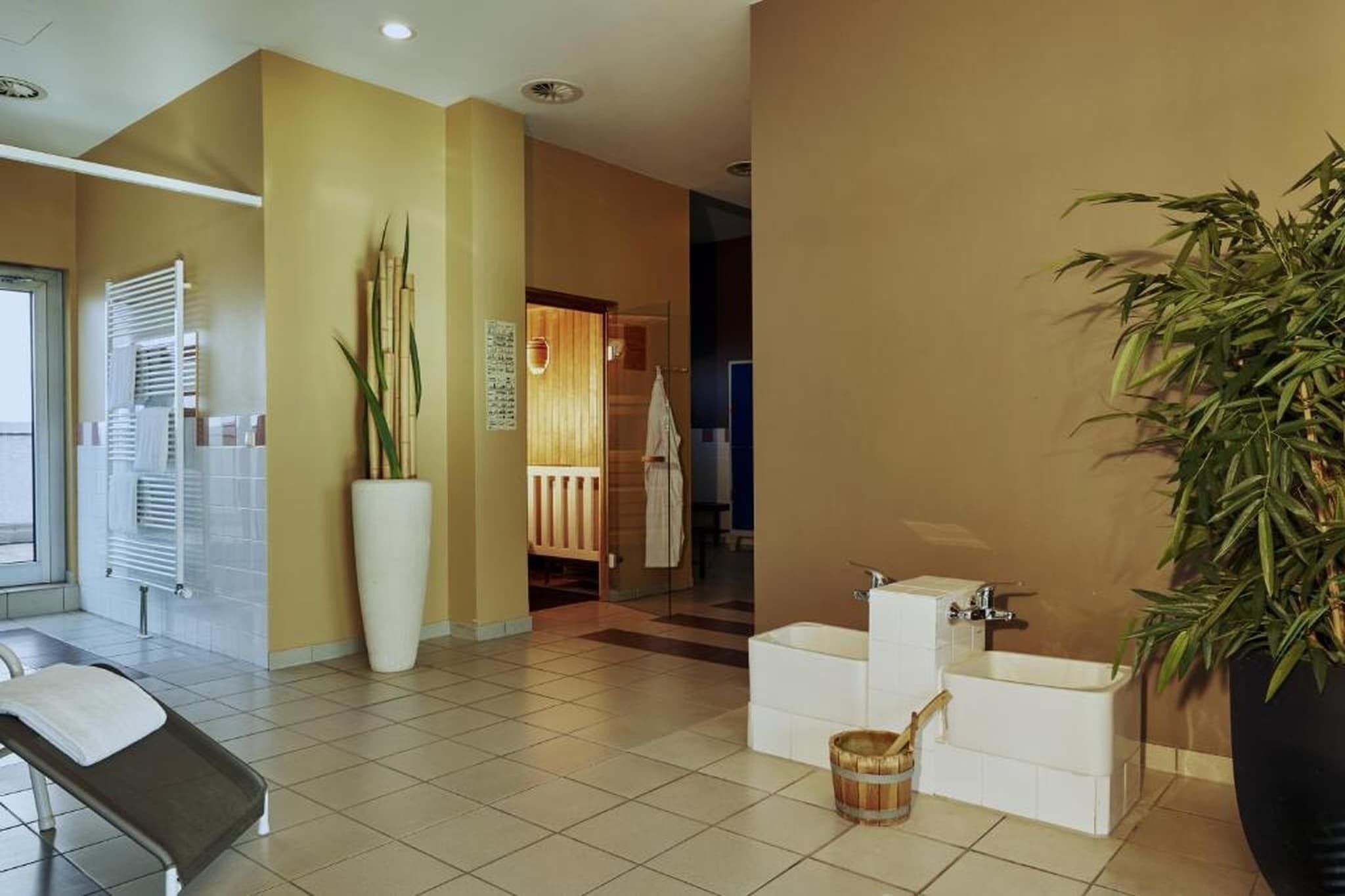 A hotel lobby with a reception desk, a large potted plant, a reception area, and a visible bathroom with a bathtub.