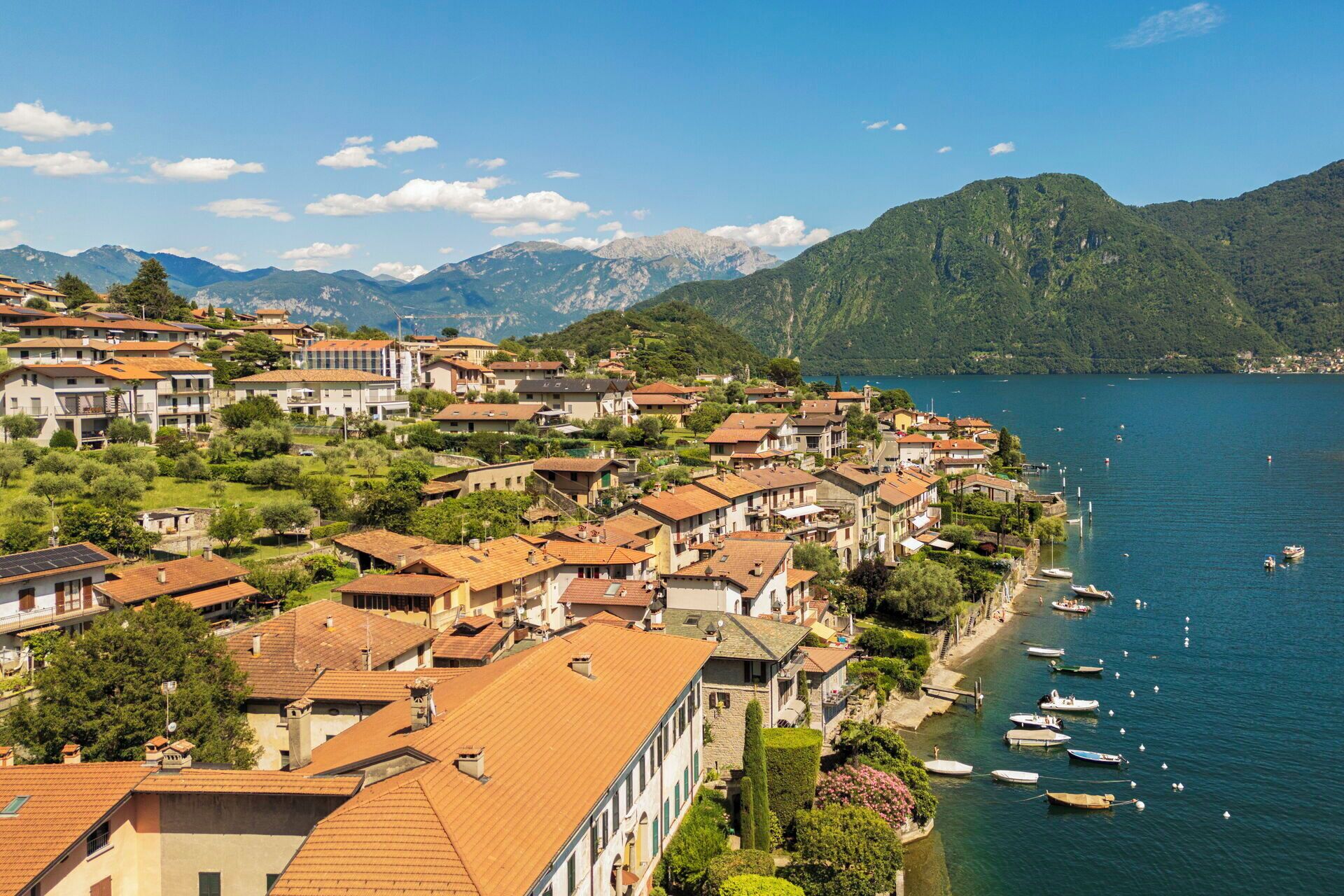 Un área residencial junto al lago, con edificios, barcos y montañas al fondo.
