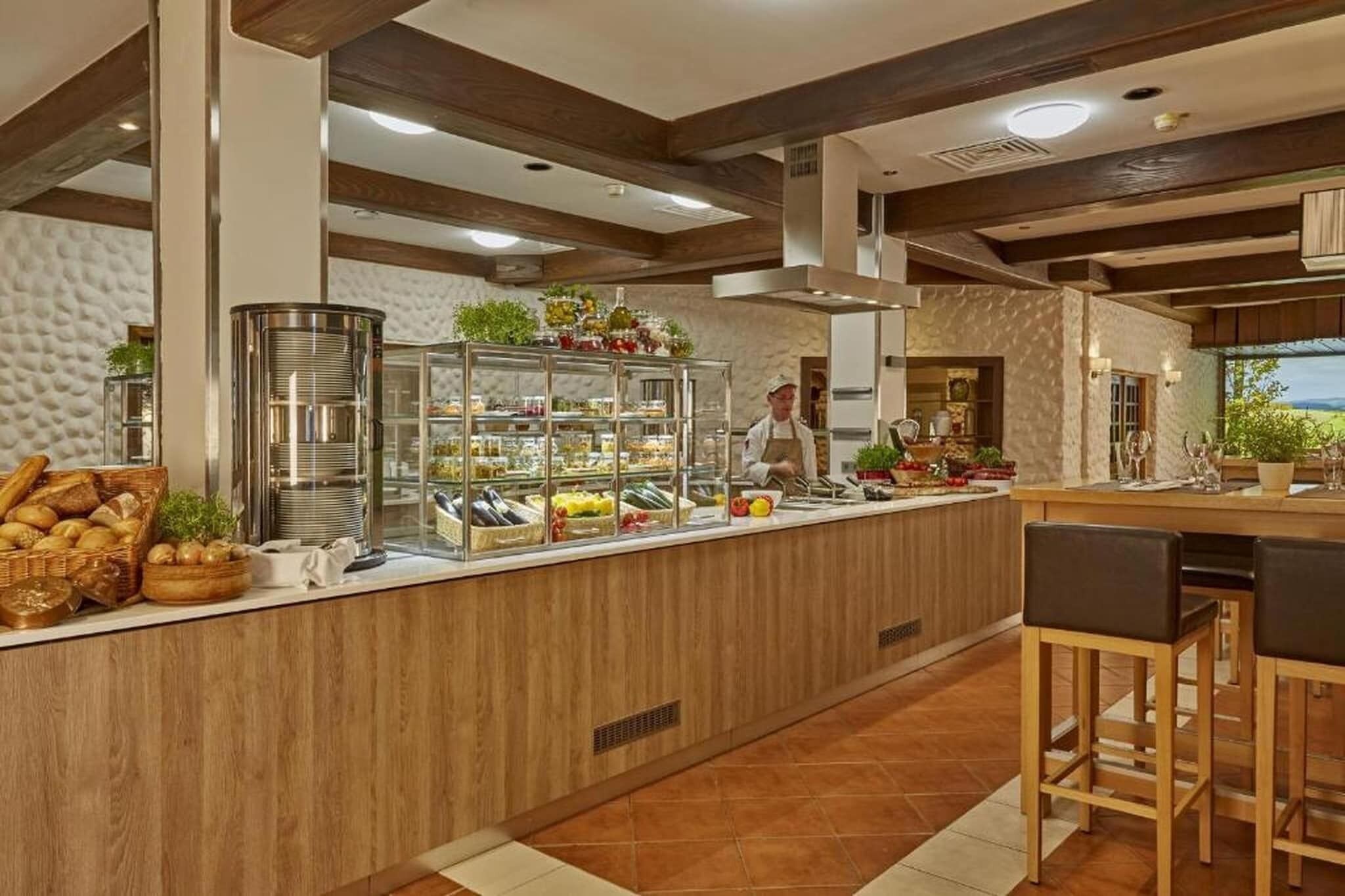 Ein Buffet mit verschiedenen Speisen, eine Bar mit Hockern und Blick ins Freie.