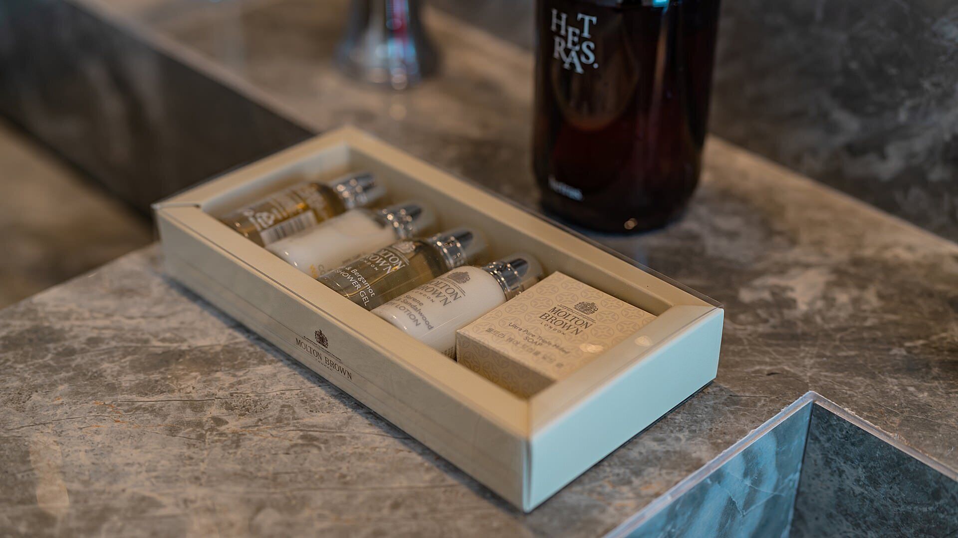 Una caja de madera con varios artículos de aseo personal sobre una encimera de mármol.