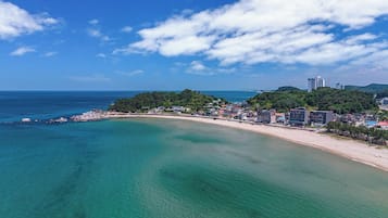 Un pueblo costero con playa, aguas cristalinas y una combinación de edificios residenciales y comerciales.