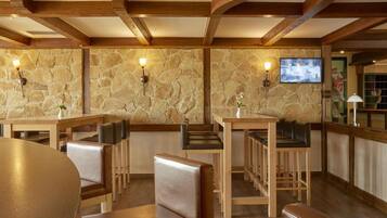 A restaurant with stone walls, wooden beams, and a TV mounted on the wall.
