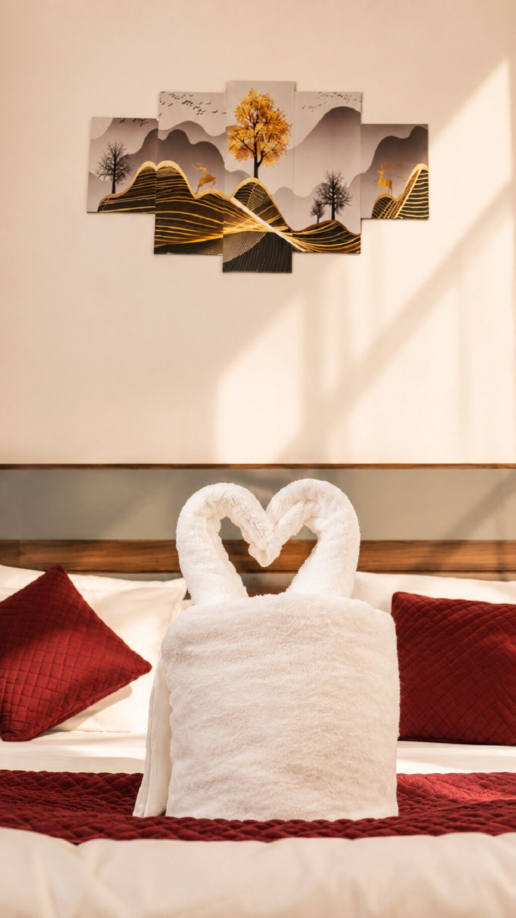 A hotel room with a bed, a heart-shaped towel, and a wall art piece.
