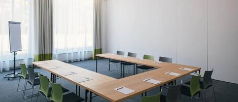 A conference room with a long table, green chairs, a whiteboard, and a projector.