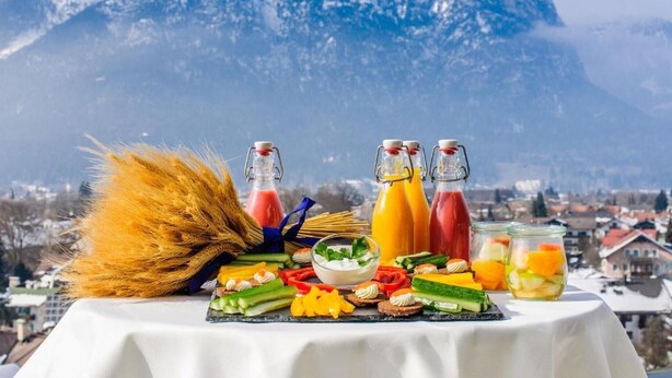 A table with food and drinks, a broom, and a mountainous backdrop.